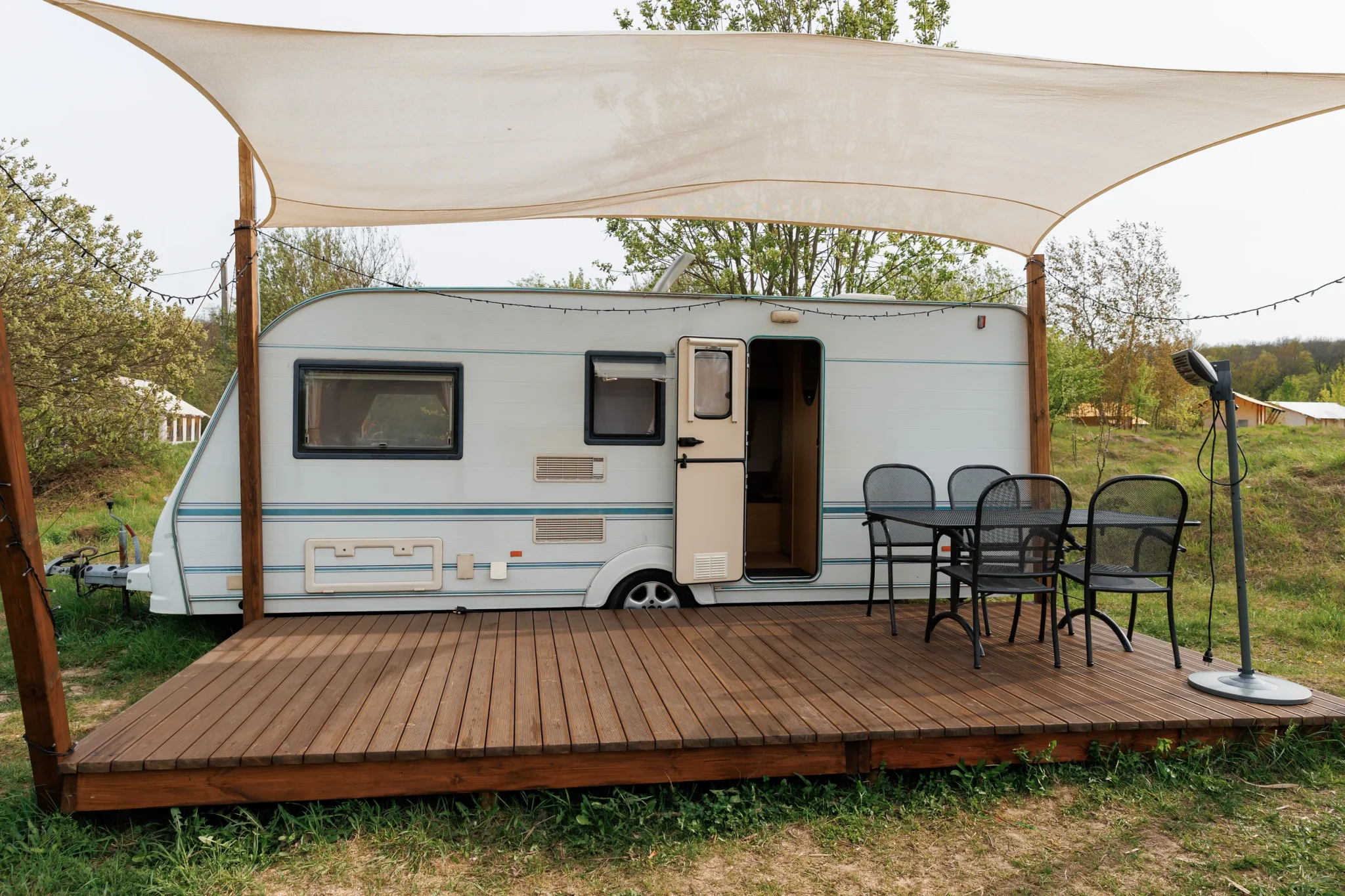 RV parked with a tent, table, and chairs in front