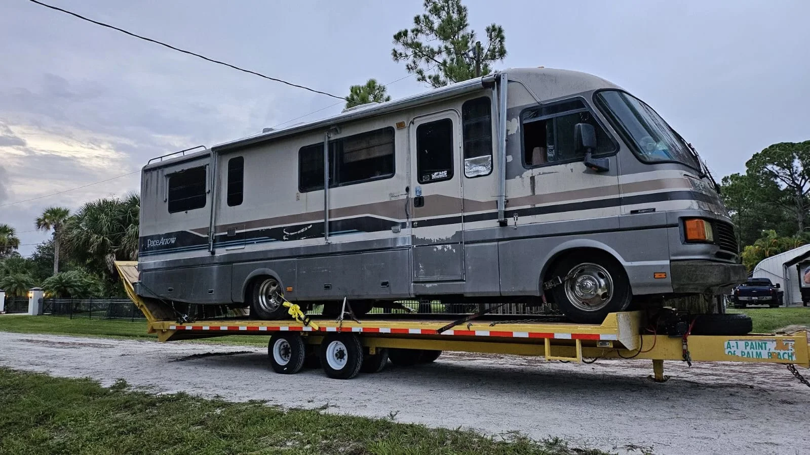 Truck towing an RV on a flatbed, moving along the road